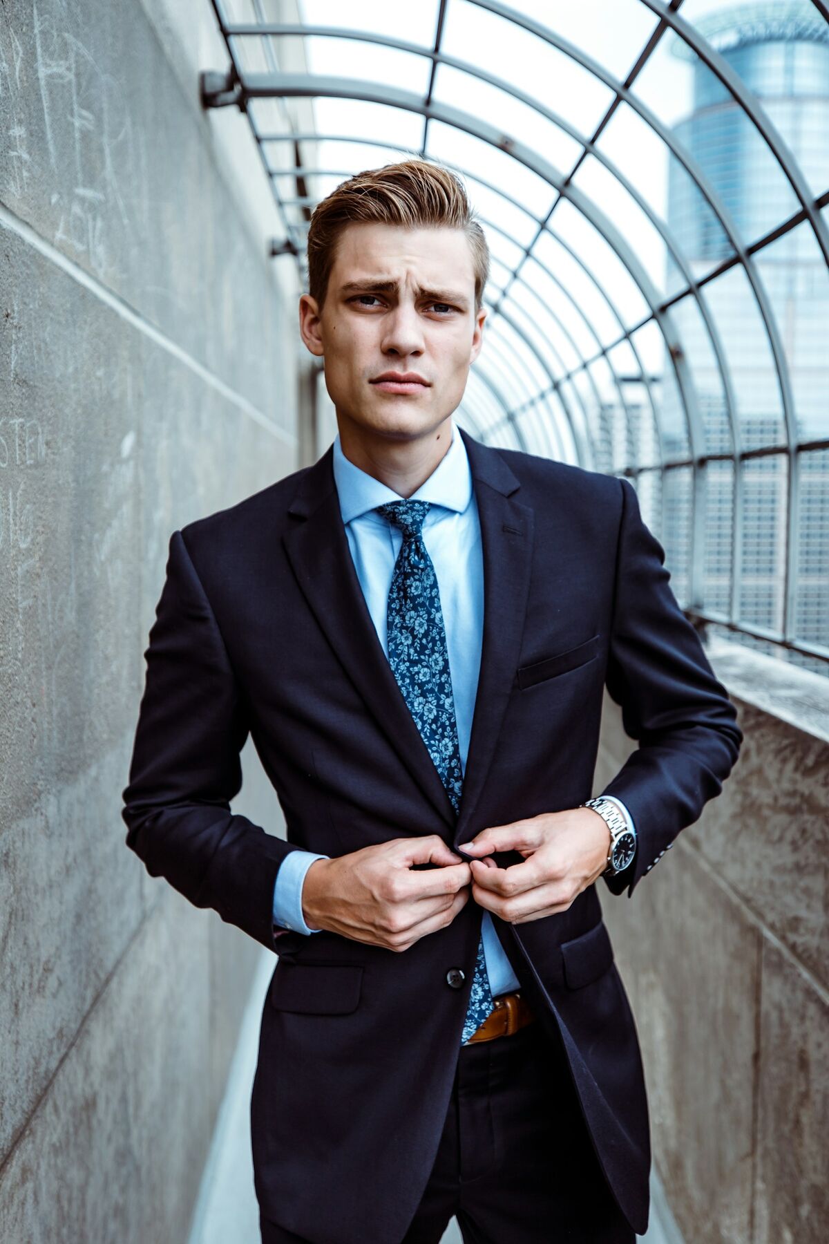 A collector fastening a suit jacket, watch on wrist